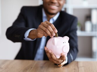 cropped-of-black-businessman-putting-money-in-pigg-2022-02-05-00-37-43-utc